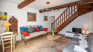 A living room with a sofa, a dining table with chairs, a small coffee table, a TV, and a staircase. - A peaceful house in Provence with a pool, located between the Luberon, Avignon, and Mont Ventoux (Monteux)