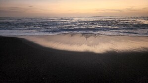 Ein Strand bei Sonnenuntergang, mit Wellen.