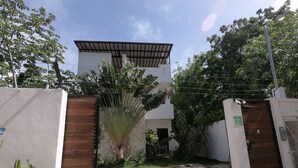 Un bâtiment moderne doté d’une entrée sécurisée par un portail, d’un patio couvert et d’une allée gravillonnée.
