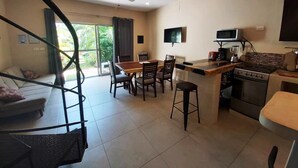 Une cuisine moderne avec un coin repas, un escalier et un téléviseur fixé au mur.
