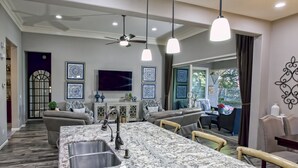 A spacious kitchen with a large island, modern pendant lights, and a ceiling fan.