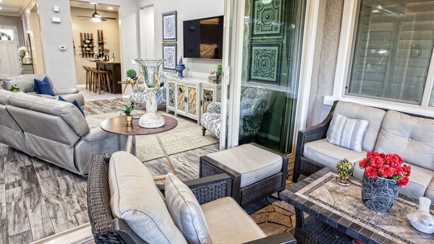 A modern living room with a grey sectional sofa, a wicker coffee table, and a patterned rug.