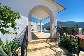 A stone staircase leading to a pool area with a clear view of mountains in the background. - Villa Zea Mountain View with Private Pool (Chania)