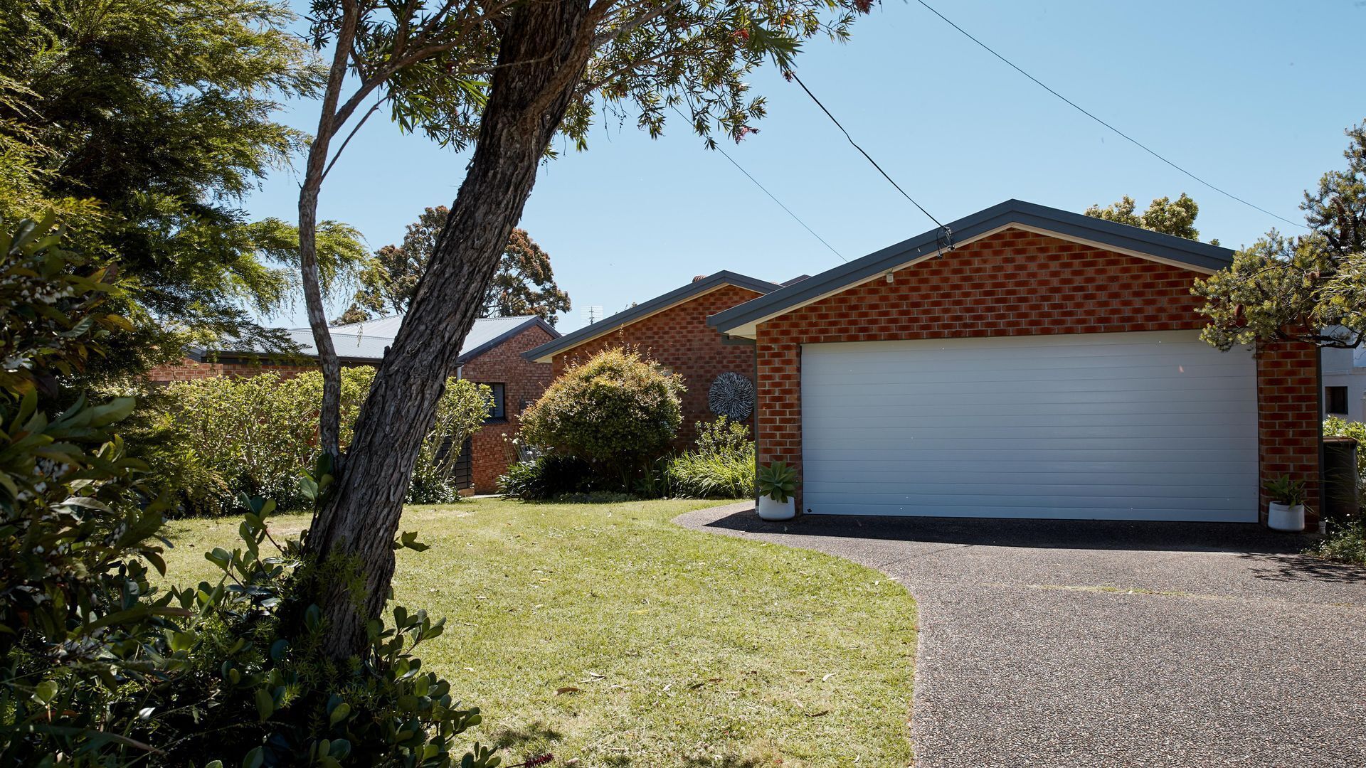 A residential area with brick houses, a white garage door, and a well-maintained lawn.