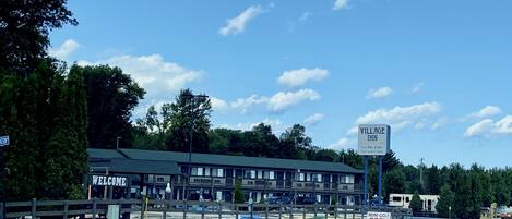 A Village Inn motel with a "Welcome" sign, a "Mini Golf Open to Public" sign, and a sign indicating it's "On the Lake."