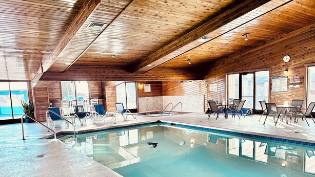 An indoor swimming pool with clear water, wooden walls, and a tiled floor.