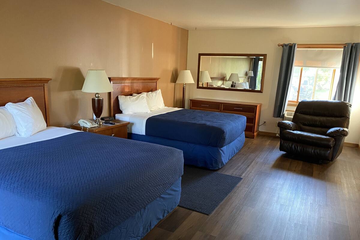 Ein Hotelzimmer mit zwei Betten, einem Schreibtisch, einem Stuhl, einem Schminktisch und einem großen Spiegel.