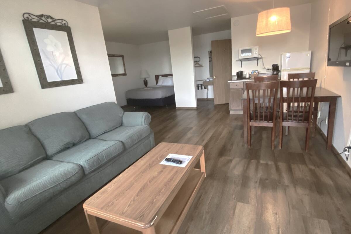 Ein modernes Wohnzimmer mit grauem Sofa, einem Holztisch und einem Essbereich mit Holztisch und Stühlen.