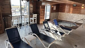 A wooden interior with a pool area, lounge chairs, and a table with chairs.
