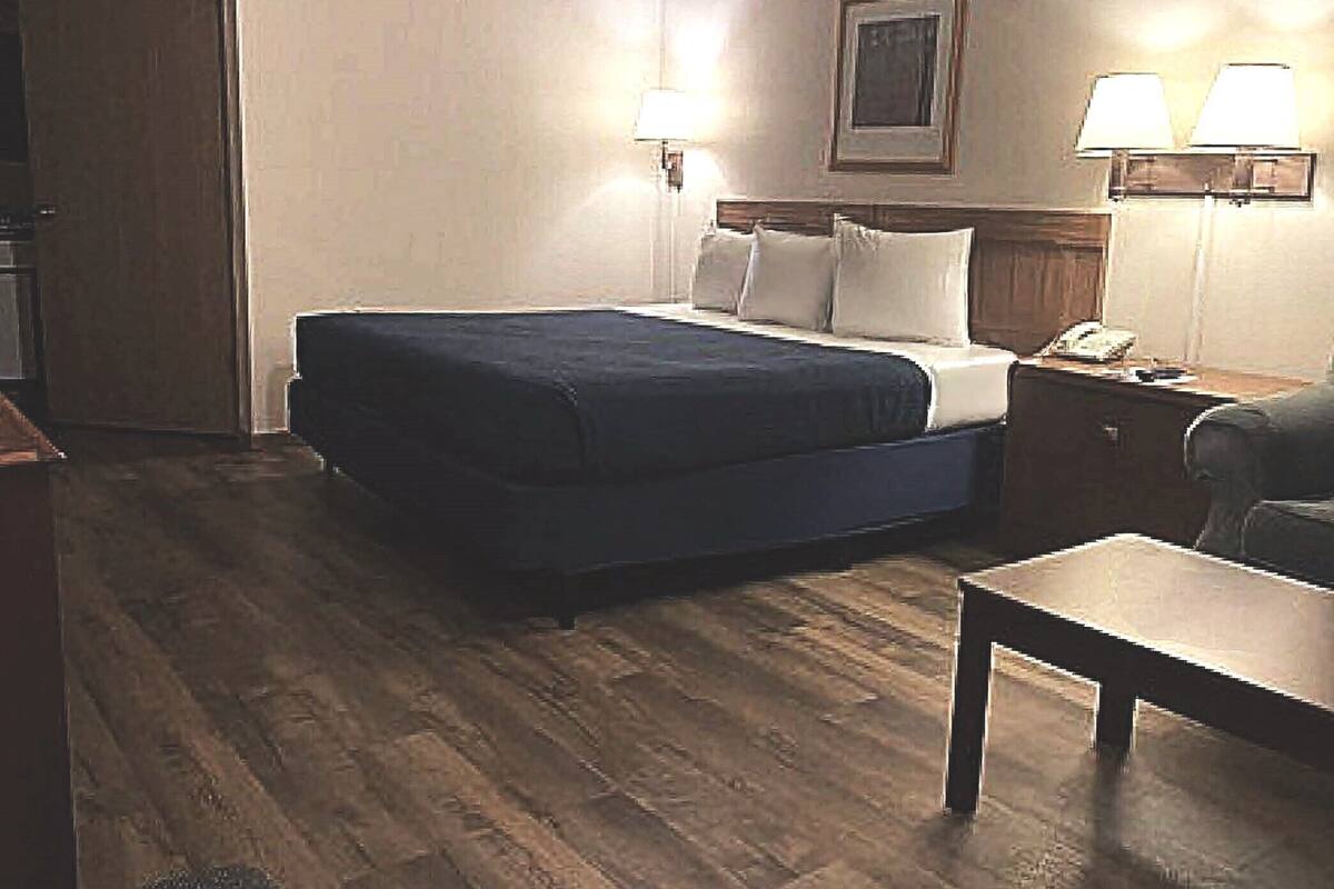 Ein Hotelzimmer mit einem Bett, Nachttischlampen, einem Schreibtisch und einem Sessel.