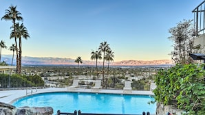 A pool with a 'KEEP CLOSED' sign, palm trees, and a mountainous view.