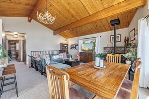 Ein gemütliches Interieur mit Holzbalkendecke, einem Esstisch und einem Kamin.