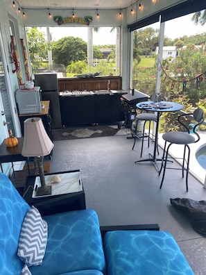 A covered outdoor area with a bar, seating, and a view of the garden. - Peaceful Paridise (Sarasota)