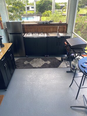 A compact kitchen with a gas stove, a refrigerator, and a grill. - Peaceful Paridise (Sarasota)