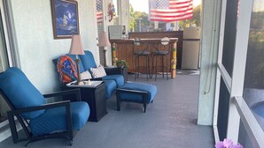 A covered outdoor seating area with blue chairs and a bar area in the background. - Peaceful Paridise (Sarasota)