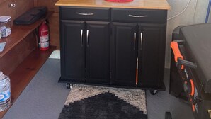 A compact kitchen with a microwave, coffee maker, and a small refrigerator. There is a window with blinds, a red lobster decoration, and a black rug on the floor. - Peaceful Paridise (Sarasota)