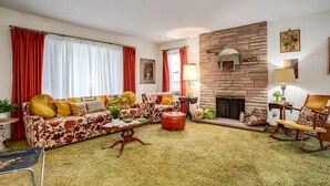 A living room with a sofa, armchairs, a coffee table, and a fireplace.
