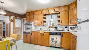 A compact kitchen with wooden cabinets, a vintage refrigerator, and a dishwasher.