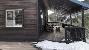 Une cabane en bois avec un porche couvert, une fenêtre avec des stores et une chaise.