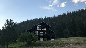 Une cabane à deux étages dotée d’un balcon, située au milieu d’une colline boisée.