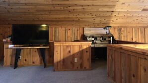 Une pièce aux murs lambrés, équipée d’un téléviseur à écran plat, d’un meuble en bois et d’un petit coin cuisine.