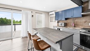 Una cucina moderna con un'isola grande, mobili blu e vista su un balcone.