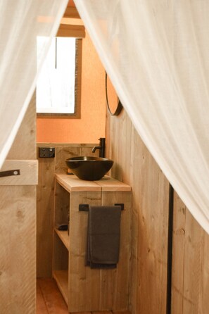 Una cabaña de madera con un lavabo negro en un estante, una ventana y una toalla colgada en un perchero.