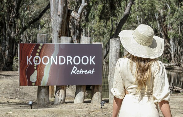 Letrero de Koondrook Retreat, con un fondo de madera rústica y una mujer al frente.