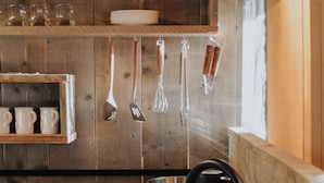 A kitchen with wooden walls, a stainless steel sink, hanging utensils, and a kettle. - Koondrook Retreat (Koondrook)