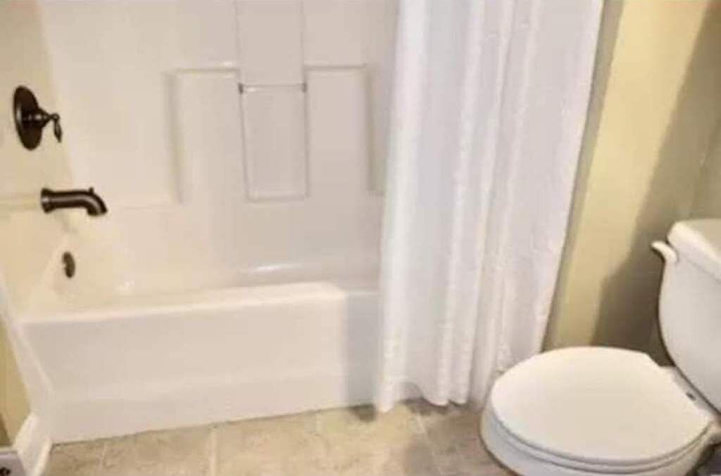 Un bagno con una vasca, un WC e una tenda da doccia.
