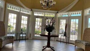 Une pièce spacieuse avec un sol carrelé, une table ronde ornée d’un vase de fleurs et deux fauteuils.