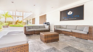 Un espace de détente moderne, avec des meubles en osier, un grand logo sur le mur et une vue sur l’extérieur.