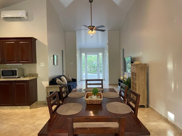 A spacious kitchen with a dining area, wooden cabinets, a microwave, and a ceiling fan.