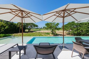 A poolside area with two umbrellas, a table, and chairs.