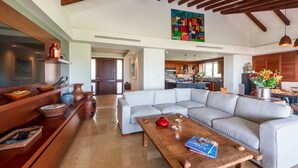A spacious living area with a large sectional sofa, wooden coffee table, and a kitchen in the background. - PH Vista Encanto in El Encanto by Mita Residential. Golf & Ocean View, Pool, Golf Cart (Punta Mita)