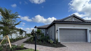Een woonhuis met garage, verharde oprit en een aangelegde tuin.