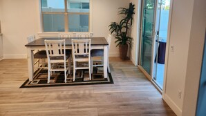 A dining area with a table and chairs, a large window, and a potted plant. - Madison's Place<br>Cozy & Comfortable Modern Home (Paramount)