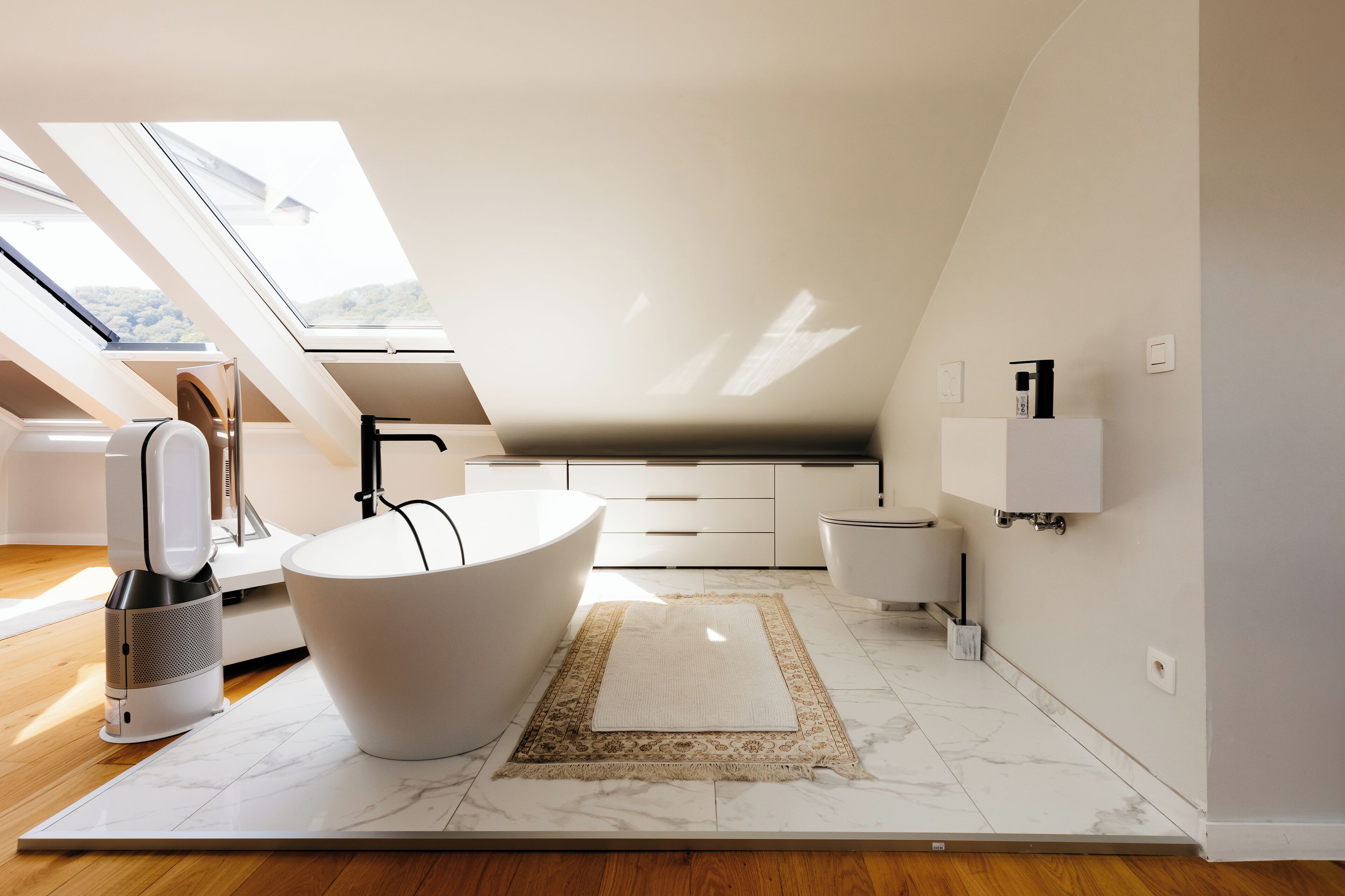 A modern bathroom with a freestanding bathtub, a large mirror, and a skylight.