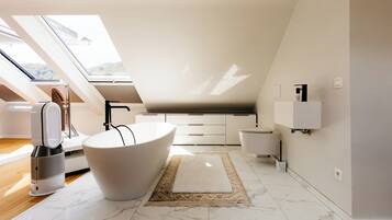 A modern bathroom with a freestanding bathtub, a large mirror, and a skylight.