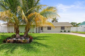 A single-story house with a well-maintained lawn and a palm tree in the front yard.