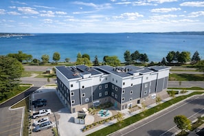 A multi-story hotel with a rooftop terrace, parking lot, and a view of the sea. - 🌆 539 Bay St Lakeview Condo | Walk to Downtown & Beach (Traverse City)