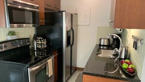 A kitchen with stainless steel appliances, a coffee maker, and a fruit bowl. - Beautiful Modern Condo Downtown/Convention Center (Seattle)