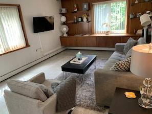 Relax in a spacious living room with a large window, flat-screen TV, and comfortable seating area.