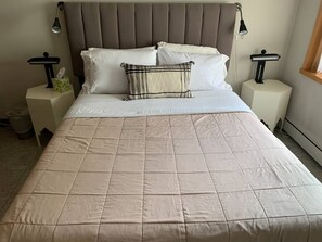 Cozy bedroom with a large bed and two nightstands, each with a lamp and a tissue box.