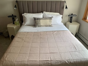 Cozy bedroom with a large bed and two nightstands, each with a lamp and a tissue box.