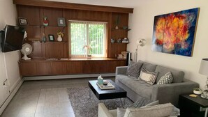 A living room with a sofa, a coffee table, a TV, and a bookshelf. - Beautiful Modern Condo Downtown/Convention Center (Seattle)