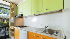 A kitchen with green upper cabinets, an orange lower cabinet, a stainless steel sink, and a gas stove.