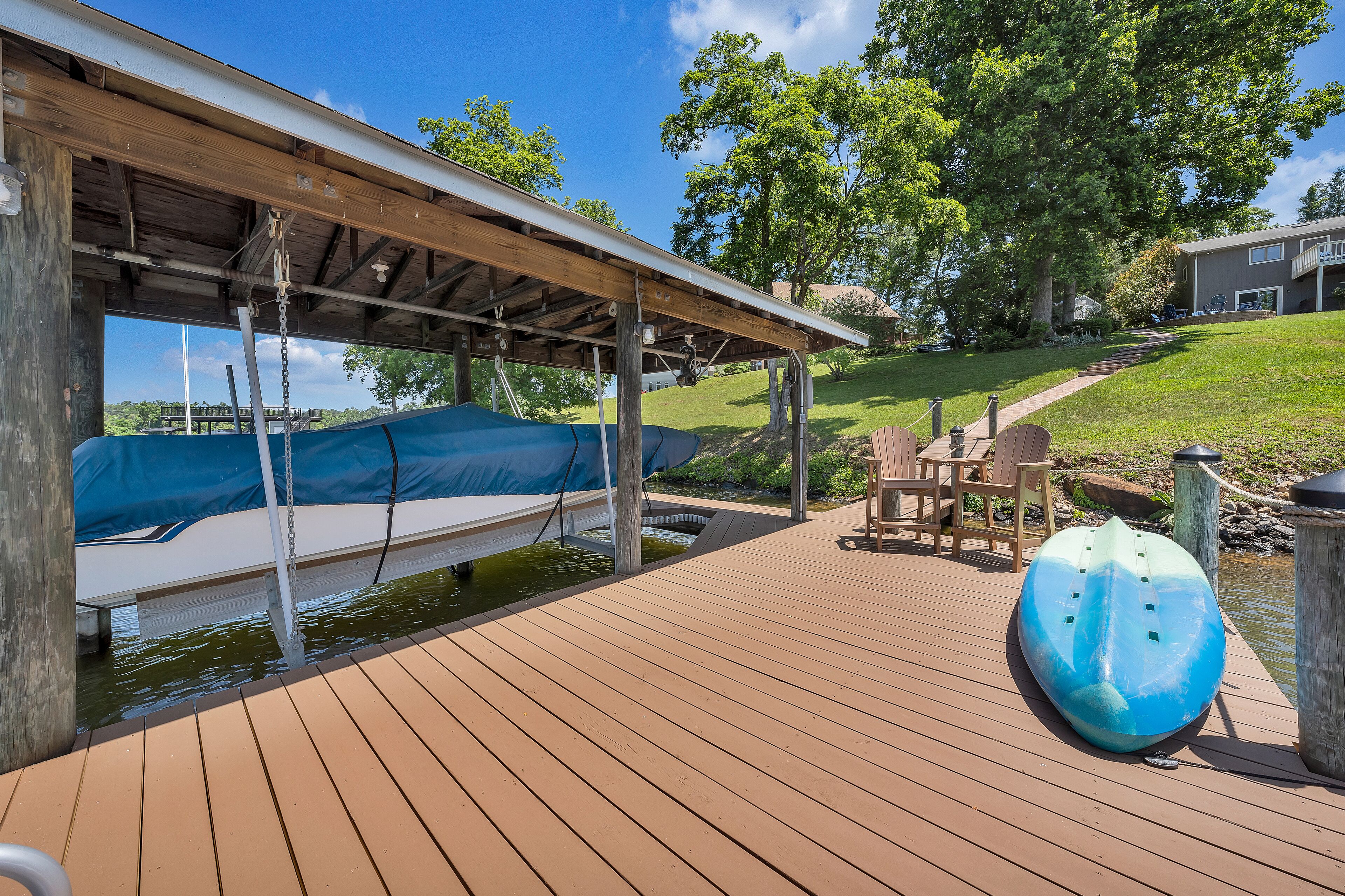 A wooden deck with a covered area, a kayak, and a chair.