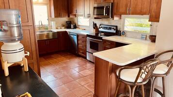 Enjoy cooking in this well-equipped kitchen with a central island, bar stools, stainless steel sink, oven, and microwave.