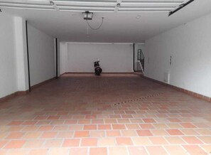 Un espacio interior amplio con piso de baldosas, una lámpara en el techo y una motocicleta en el centro.